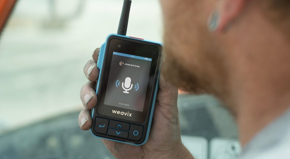 A frontline worker uses the push-to-talk (PTT) capabilities of the Walt Smart Radio to communicate with one of their co-workers. Countless interactions like this one can create a better frontline employee experience on your worksite.