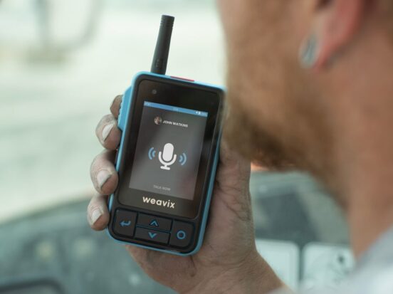 A frontline worker uses the push-to-talk (PTT) capabilities of the Walt Smart Radio to communicate with one of their co-workers. Countless interactions like this one can create a better frontline employee experience on your worksite.