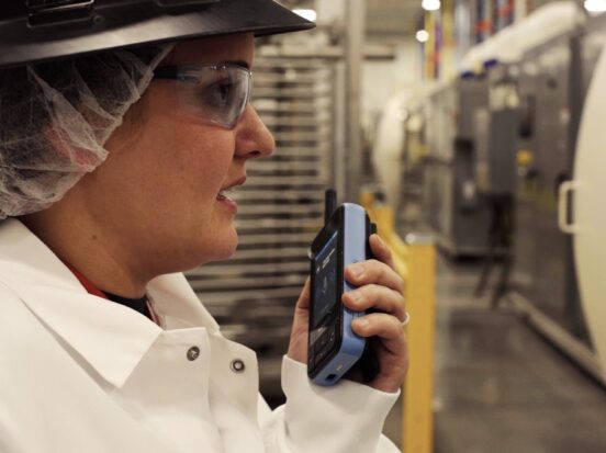 Cover image for a blog highlighting the difference between the Internet of Things (IoT) and the Internet of Workers (IoW), featuring a worker holding a Walt smart radio