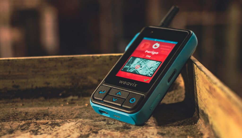 Walt Smart Radio devices translate a safety alert, with a red screen displaying "Perigo" and a fire icon.