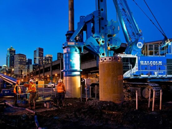 Malcolm drilling frontline workers working in front of a city skyscraper background