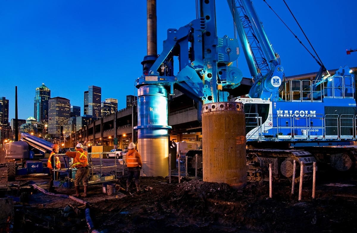 Malcolm drilling frontline workers working in front of a city skyscraper background