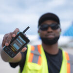 A PrimeFlight Aviation employee holds up a Walt Smart Radio on the tarmac