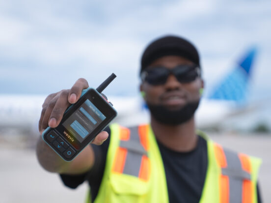 A PrimeFlight Aviation employee holds up a Walt Smart Radio on the tarmac