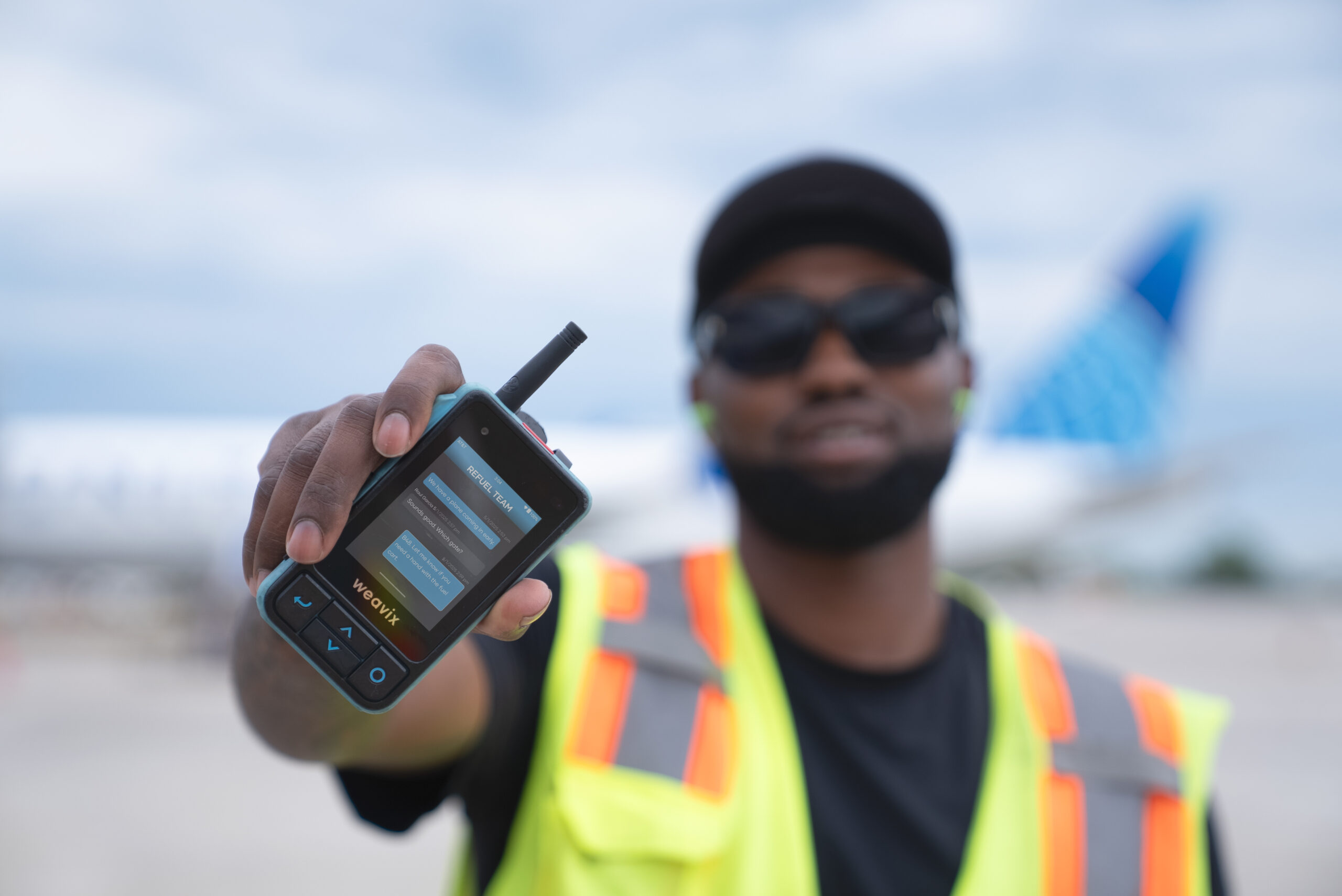 A PrimeFlight Aviation employee holds up a Walt Smart Radio on the tarmac