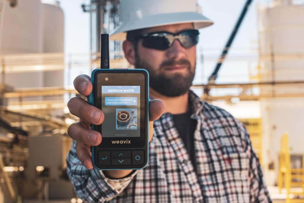 Frontline worker holding up a Walt Smart Push to Talk Radio by weavix