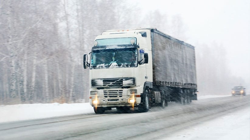 Truck driving through bad snow weather