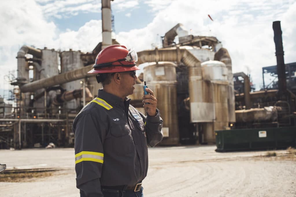 Frontline worker using a Walt Smart Radio by weavix to communicate in a refinery