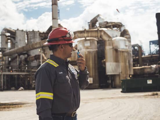 Frontline worker using a Walt Smart Radio by weavix to communicate in a refinery