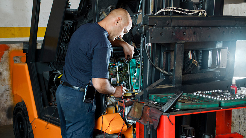 Maintenance worker fixing a fork lift