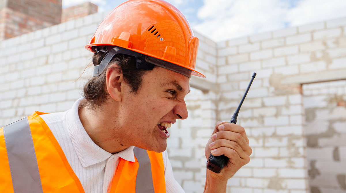Construction worker shouting at a walkie talkie