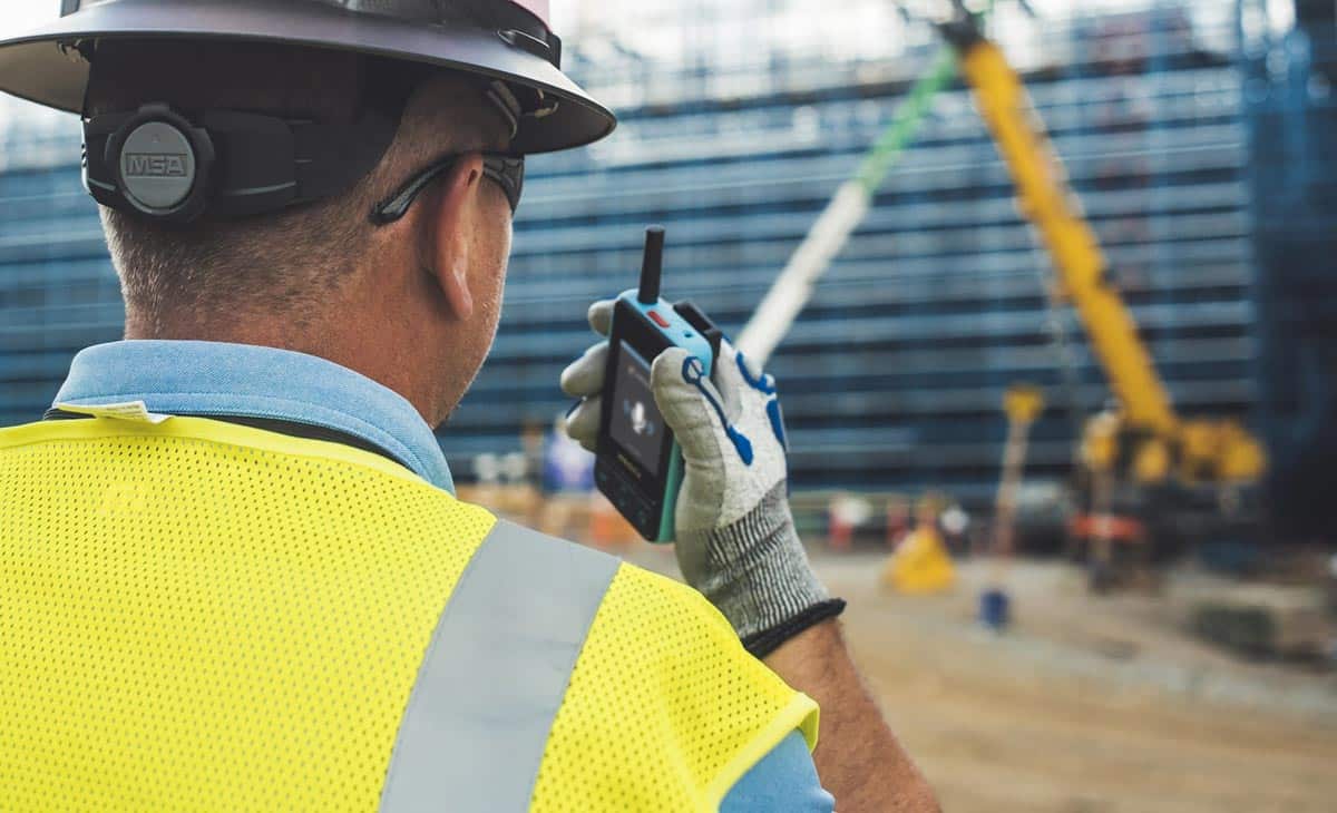 Construction worker using the push-to-talk feature on the Walt Smart Radio